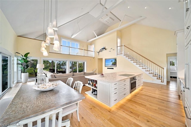 dining area featuring high vaulted ceiling and light hardwood / wood-style flooring