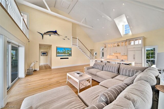 living room with high vaulted ceiling, light hardwood / wood-style floors, and beam ceiling