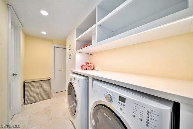 clothes washing area with light tile patterned flooring and washer and dryer