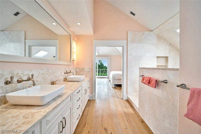 bathroom with dual vanity, lofted ceiling, hardwood / wood-style floors, and tile walls