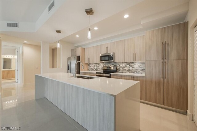 kitchen featuring stainless steel appliances, sink, decorative light fixtures, decorative backsplash, and light tile patterned flooring