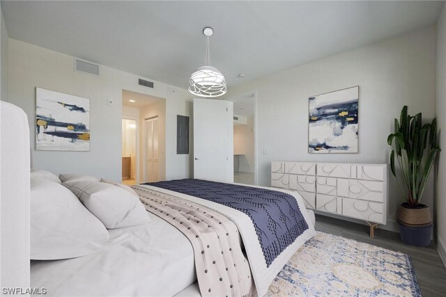 bedroom with wood-type flooring, electric panel, and ensuite bath