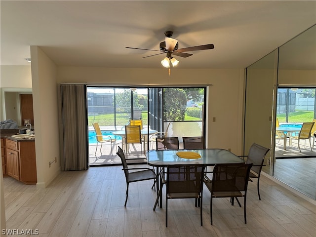 dining room with sink, light hardwood / wood-style flooring, ceiling fan, and plenty of natural light