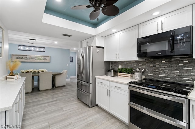 kitchen featuring decorative backsplash, stainless steel appliances, a raised ceiling, and white cabinets