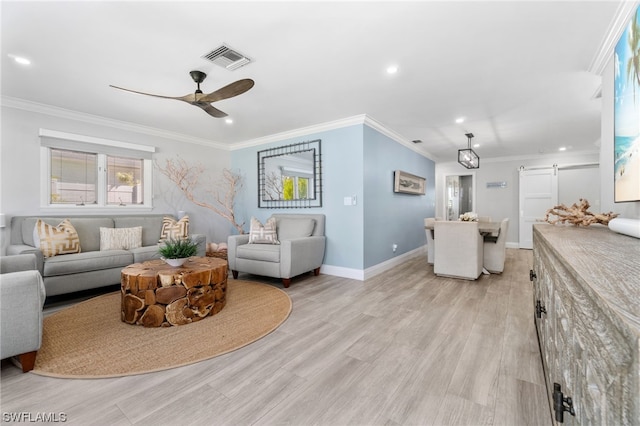 living room with ceiling fan, ornamental molding, a barn door, and light hardwood / wood-style flooring