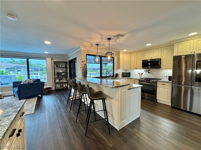 kitchen featuring a kitchen island, a breakfast bar, hanging light fixtures, light stone counters, and stainless steel appliances