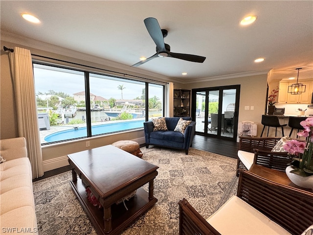 living room with crown molding, a water view, hardwood / wood-style floors, and ceiling fan