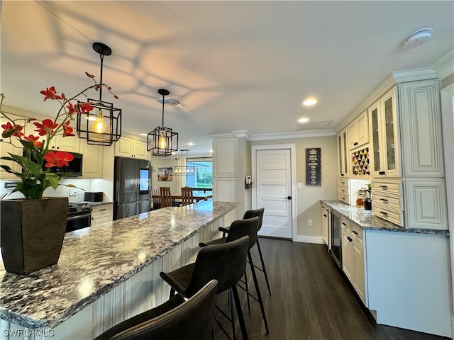 kitchen featuring white cabinetry, decorative light fixtures, stainless steel refrigerator, and dark stone counters