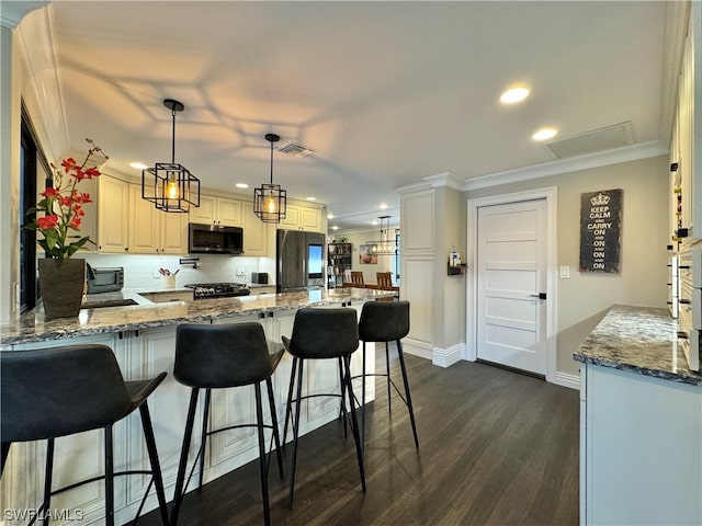 kitchen with pendant lighting, dark wood-type flooring, stainless steel fridge, light stone countertops, and kitchen peninsula