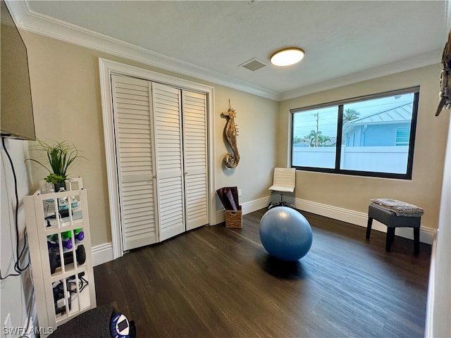 exercise room with crown molding and dark wood-type flooring