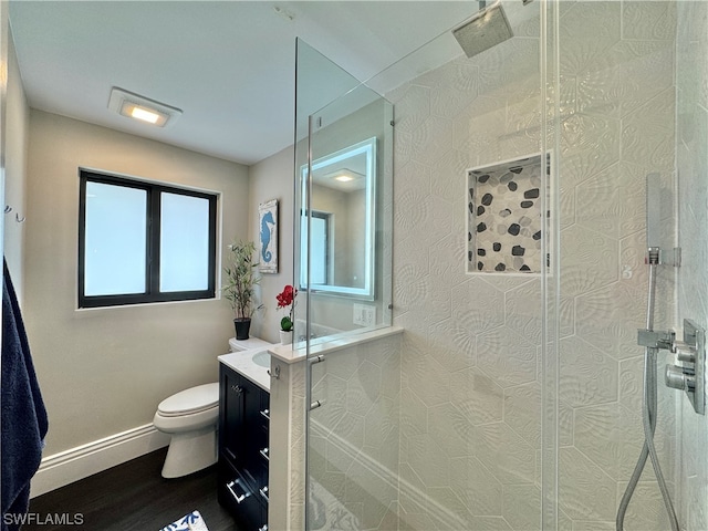 bathroom with tiled shower, vanity, toilet, and hardwood / wood-style floors