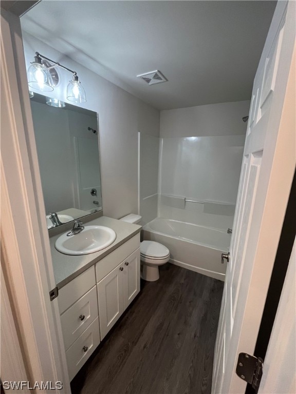 full bathroom with hardwood / wood-style floors, toilet, vanity, and shower / tub combination