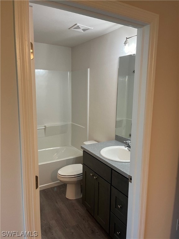 full bathroom featuring washtub / shower combination, wood-type flooring, toilet, and vanity