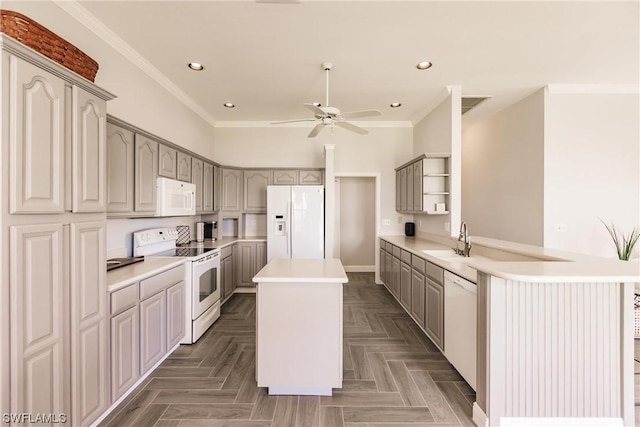 kitchen featuring white appliances, a kitchen island, ornamental molding, light countertops, and a sink