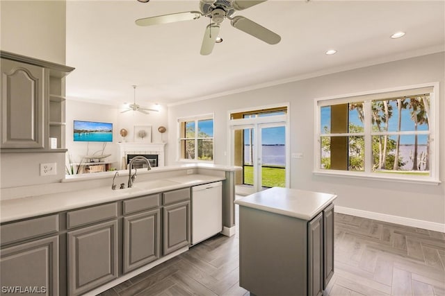 kitchen featuring dishwasher, light countertops, gray cabinets, and a sink