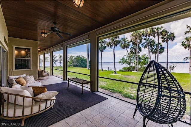 sunroom featuring a ceiling fan, wooden ceiling, and a water view