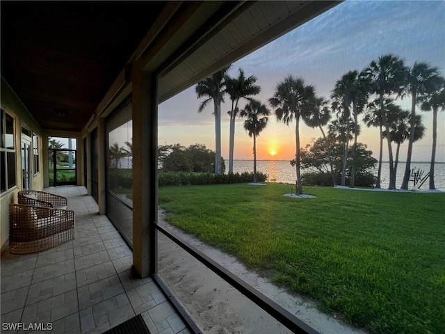 yard at dusk featuring a water view and a patio