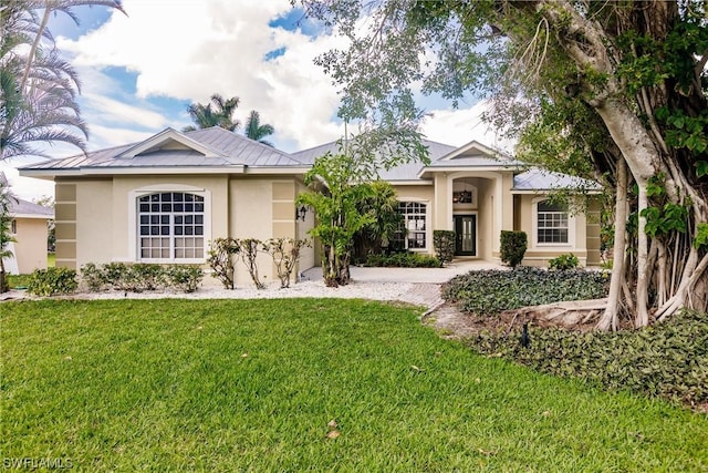 ranch-style house with metal roof, a standing seam roof, a front yard, and stucco siding