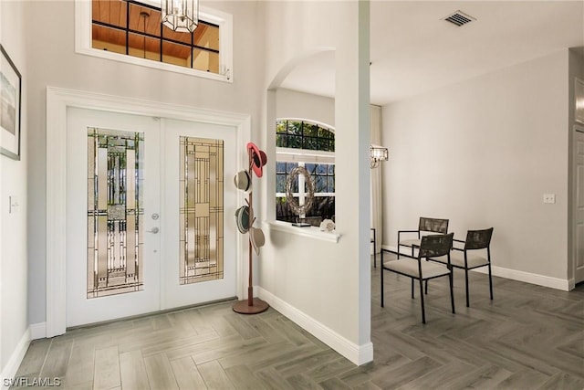 foyer featuring arched walkways, french doors, visible vents, and baseboards