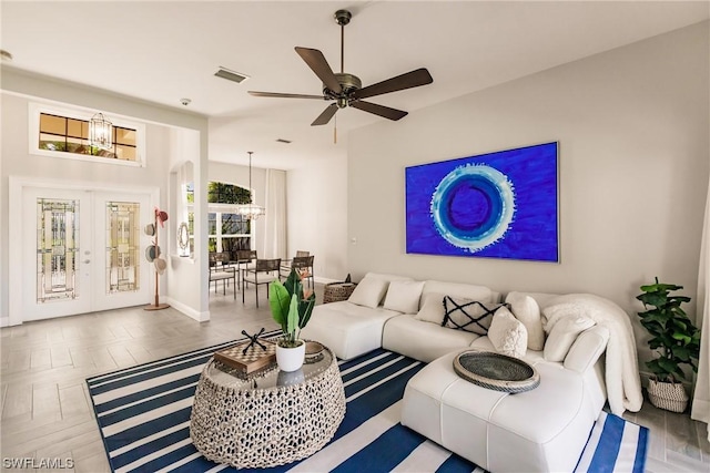 living room with ceiling fan with notable chandelier, visible vents, baseboards, and french doors