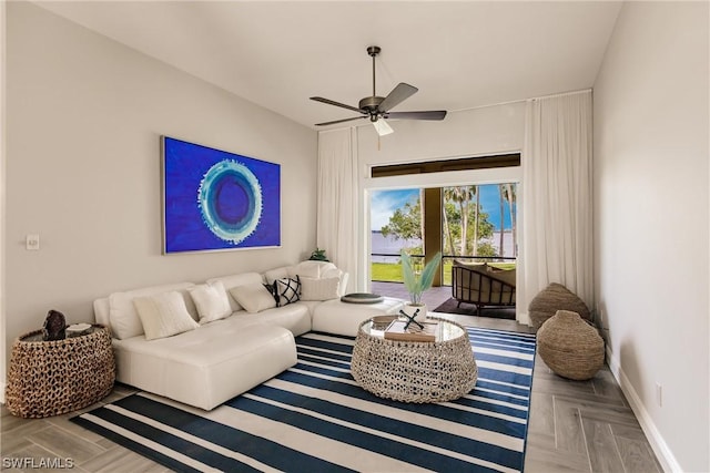 living area with a ceiling fan and baseboards