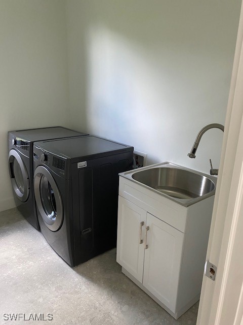 washroom featuring washing machine and dryer, cabinets, and sink