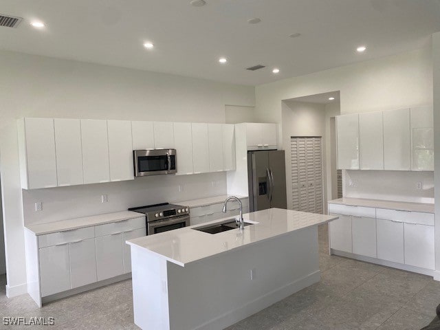 kitchen featuring an island with sink, sink, appliances with stainless steel finishes, and white cabinets