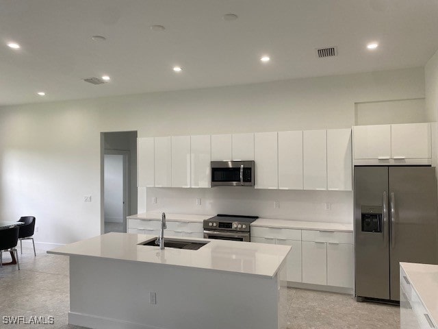 kitchen with a kitchen island with sink, appliances with stainless steel finishes, sink, and white cabinets