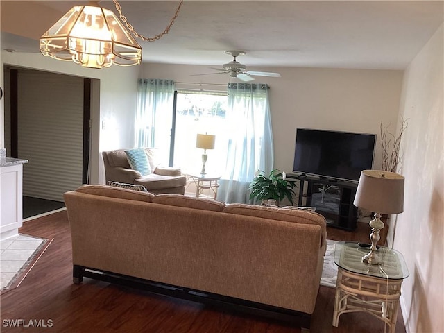 living room with dark hardwood / wood-style flooring and ceiling fan with notable chandelier