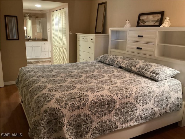 bedroom with connected bathroom, a closet, dark wood-type flooring, and sink