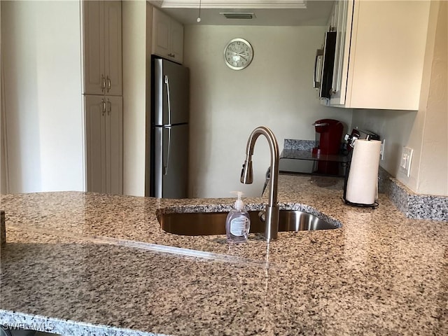 kitchen with light stone countertops, stainless steel appliances, and sink