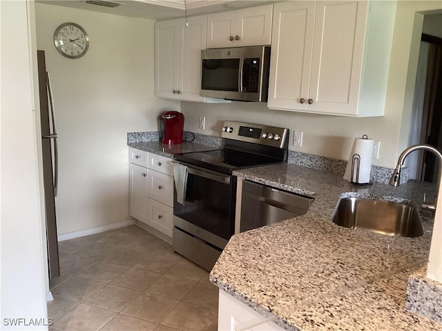 kitchen featuring white cabinetry, sink, stainless steel appliances, light stone counters, and light tile patterned floors