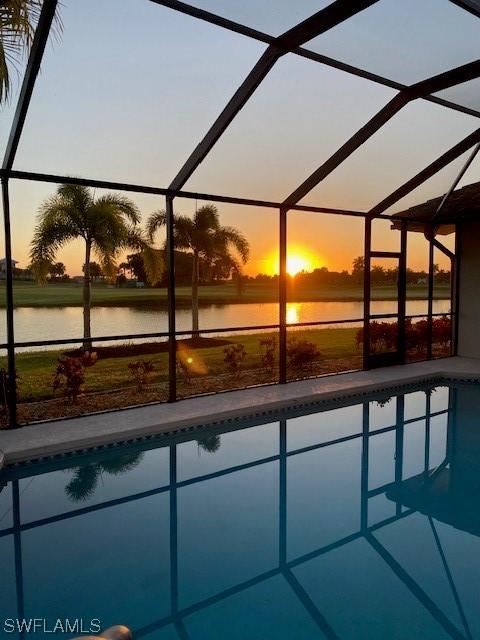 pool at dusk with a lanai and a water view