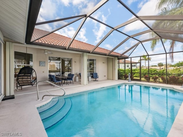 view of pool featuring ceiling fan, glass enclosure, and a patio area