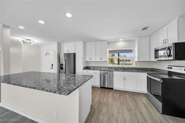 kitchen with white cabinets, appliances with stainless steel finishes, sink, and light hardwood / wood-style flooring