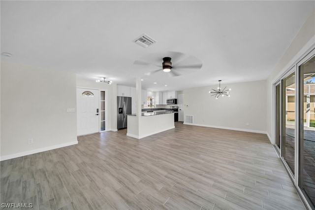 unfurnished living room featuring ceiling fan with notable chandelier and light hardwood / wood-style flooring