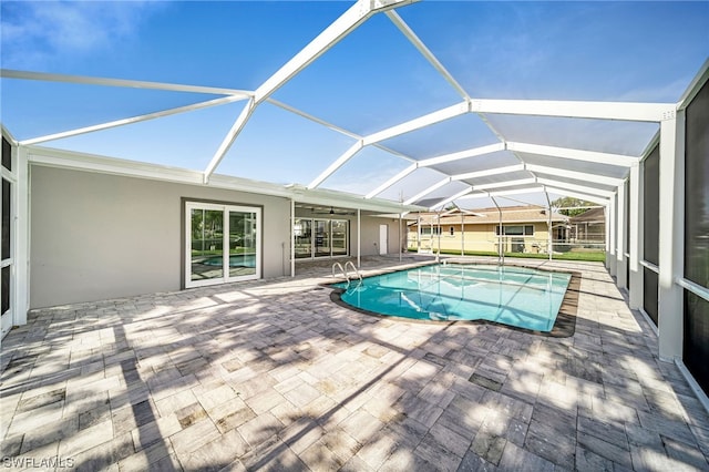 view of pool with glass enclosure and a patio area