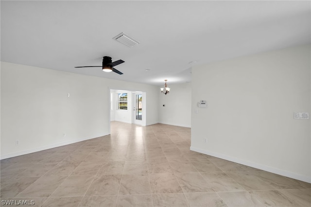 tiled spare room with ceiling fan with notable chandelier