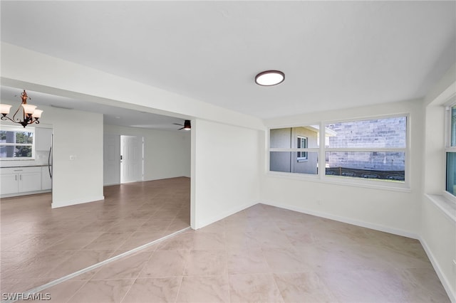 tiled spare room featuring a notable chandelier