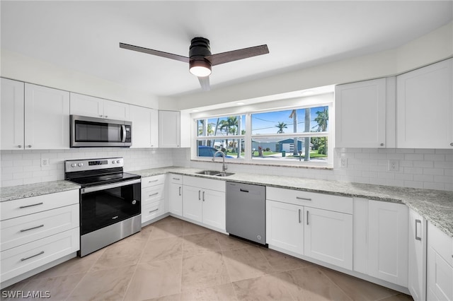 kitchen featuring backsplash, ceiling fan, stainless steel appliances, and white cabinetry