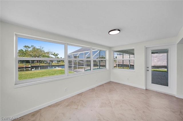 spare room with a water view, plenty of natural light, and light tile flooring