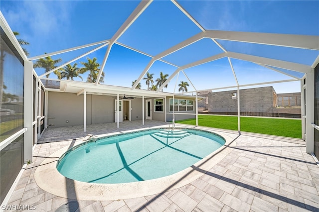 view of pool with ceiling fan, a yard, glass enclosure, and a patio