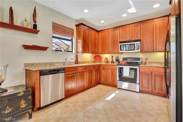 kitchen with light tile patterned floors, stainless steel appliances, light stone counters, and sink