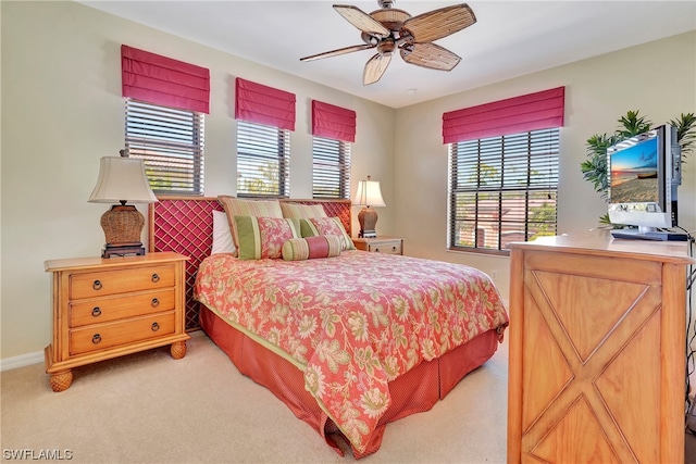 bedroom featuring ceiling fan, light colored carpet, and multiple windows