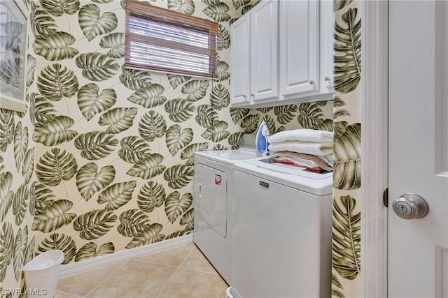 clothes washing area featuring light tile patterned flooring, cabinets, and washing machine and clothes dryer