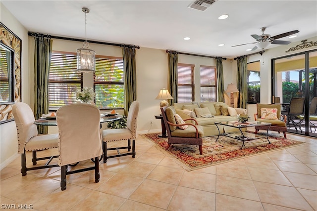 tiled living room featuring ceiling fan with notable chandelier