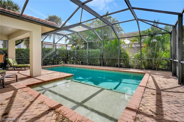 view of pool with glass enclosure and a patio area