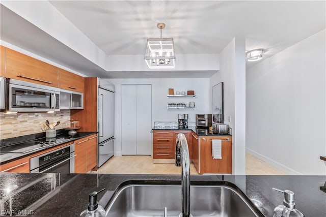 3000 Oasis Grand Blvd Unit 1507, Fort Myers, FL 33916 - kitchen with backsplash, brown cabinets, a sink, dark stone counters, and stainless steel appliances