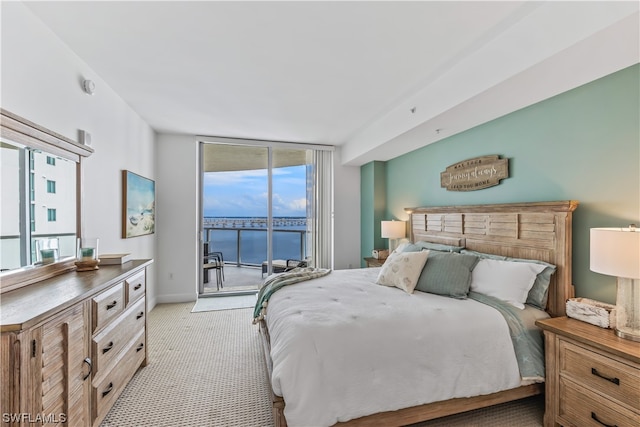 carpeted bedroom featuring expansive windows, a water view, and access to outside