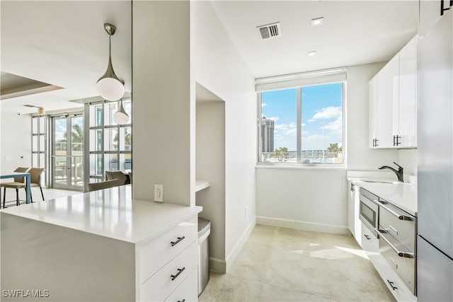 interior space with white cabinetry, sink, pendant lighting, and plenty of natural light